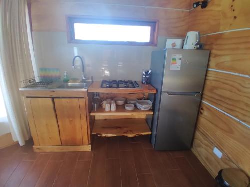 a small kitchen with a refrigerator and a sink at Cabañas Pukatue in Chonchi