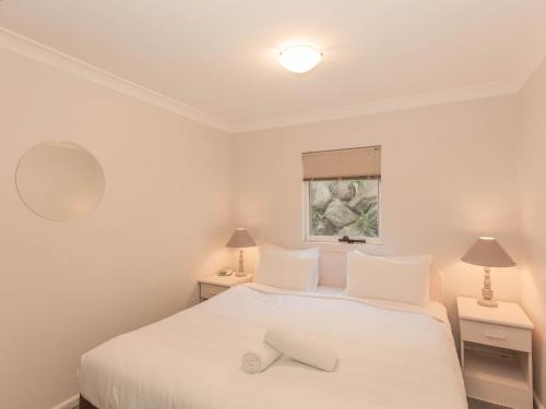 1 dormitorio con 1 cama blanca con 2 mesas y 2 lámparas en Horizons 505/10 Kosciuszko Road, en Jindabyne