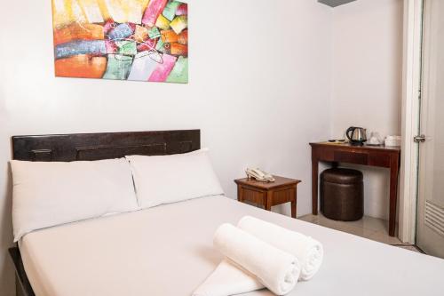 a bedroom with a white bed with a painting on the wall at GETZ HOTEL MANILA in Manila