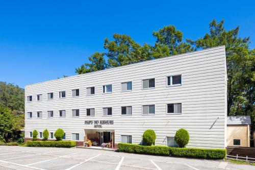 a white building with trees in the background at Hakuba Hotel Paipu no Kemuri in Hakuba