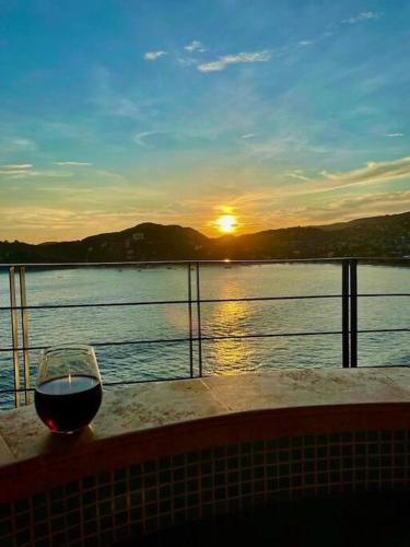 a glass of wine sitting on a table next to the water at El Nido Casa 4 in Zihuatanejo