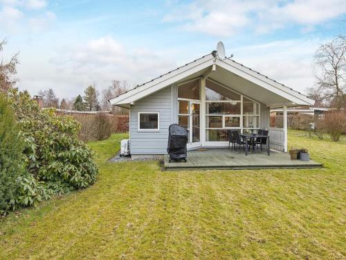 a small white cottage with a deck and a table at 6 person holiday home in Væggerløse-By Traum in Bøtø By