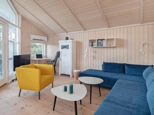 a living room with a blue couch and a yellow chair at 6 person holiday home in Væggerløse-By Traum in Bøtø By