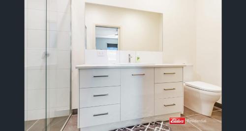 a white bathroom with a sink and a toilet at Old Port Townhouse Central to Everything in Echuca