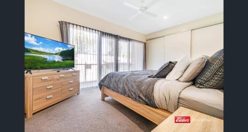 a bedroom with a bed and a flat screen tv at Old Port Townhouse Central to Everything in Echuca