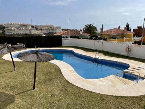 una piscina con 2 sombrillas en un patio en Casa Sonia 2 La Cala de Moral, en Cala del Moral