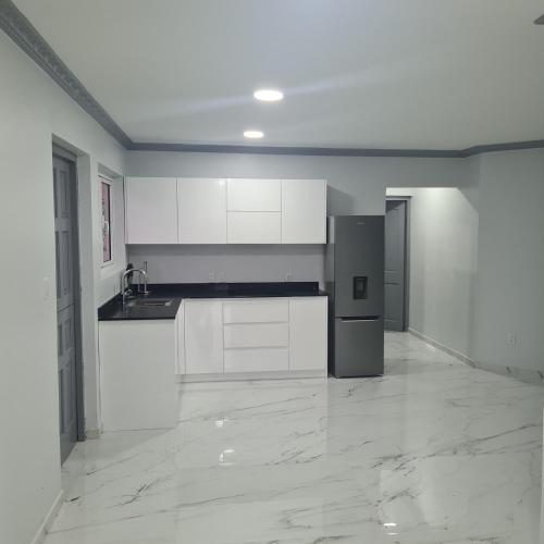 ウィレムスタッドにあるNew Modern Apartmentの白いキャビネットと冷蔵庫付きの空のキッチンが備わります。