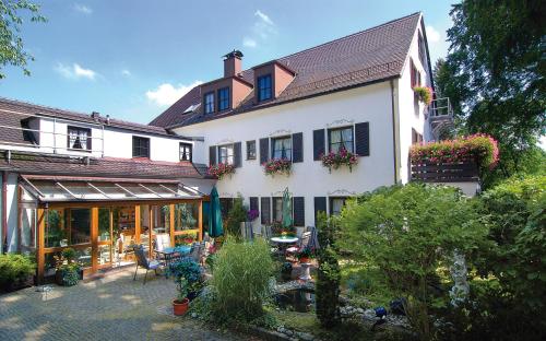 a white house with a lot of flowers in the yard at ARRIVEL Hotel am Bergson - bisher Hotel Neuner in Munich