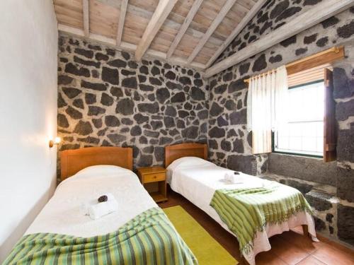 Santa LuziaにあるHoliday house, Praínha de Baixo, Pico, Azoresの石壁のベッドルーム1室(ベッド2台付)