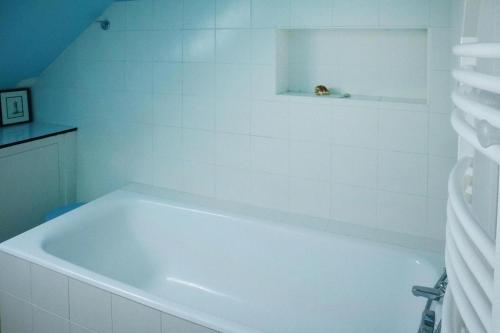 La salle de bains blanche est pourvue d'une baignoire blanche. dans l'établissement Holiday Home near St Jean du Doigt Beach, à Plougasnou