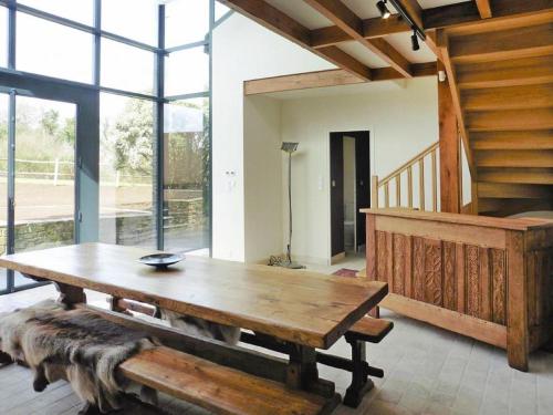Cette chambre comprend une grande table en bois et des fenêtres. dans l'établissement Estate in Landeleau near Aulne River, à Landeleau
