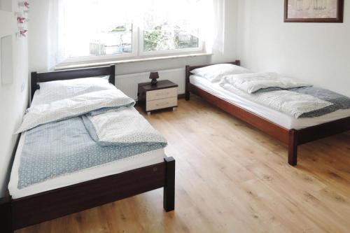 2 Betten in einem Schlafzimmer mit Holzboden in der Unterkunft Holiday flat, Stepnica in Stepnica