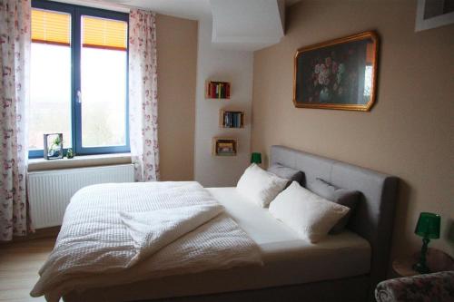 a bedroom with a bed with white sheets and a window at Holiday flat im Wasserturm Güstrow - DMS01100b-P in Güstrow