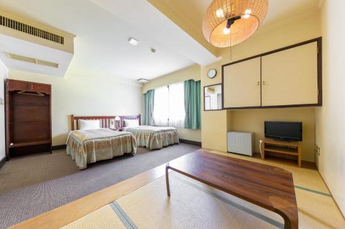 a hotel room with two beds and a flat screen tv at Hakuba Hotel Paipu no Kemuri in Hakuba