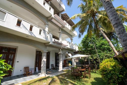 an exterior view of a house with a table and a palm tree at Plantation Surf Inn & Restaurant in Midigama