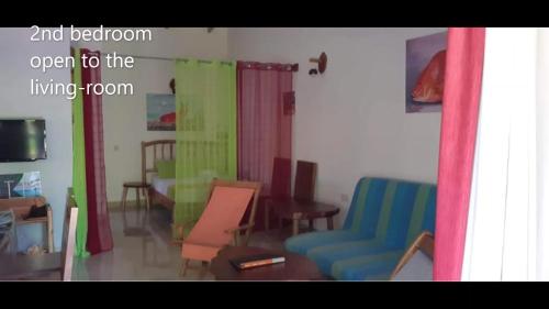 a living room with colorful curtains and a couch and chairs at La Belle Digue Don in La Digue