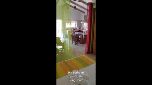 a view of a dining room and a kitchen with green curtains at La Belle Digue Don in La Digue