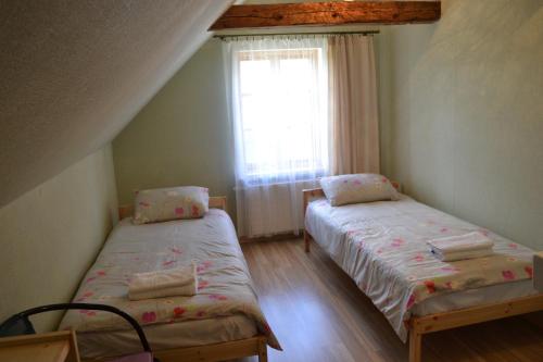 Duas camas num pequeno quarto com uma janela em Spēlmaņu krogs em Alsunga