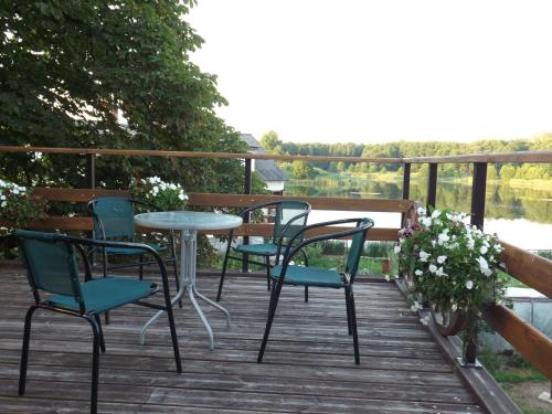 a table and chairs on a deck with a view of the water at Spēlmaņu krogs in Alsunga