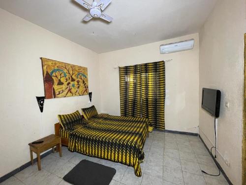 a living room with a bed and a tv at Auberge Africa Thiossane in Saly Portudal
