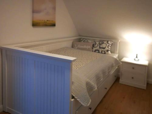 een slaapkamer met een wit bed en een nachtkastje bij Home port holiday home, Dornum in Dornumersiel