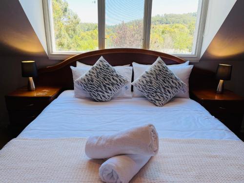 a towel laying on a bed in front of a window at Serenity in Healesville