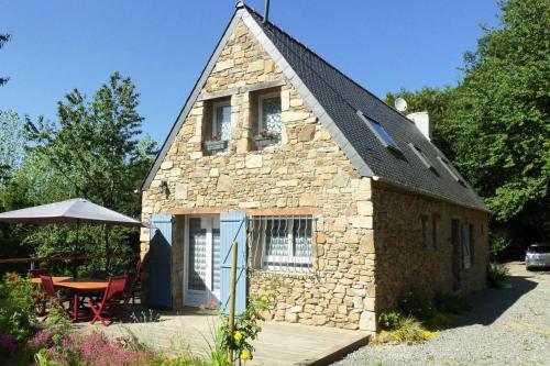 a small stone house with a table and an umbrella at Holiday Home near Rosa Granite Coast Beaches in Langoat