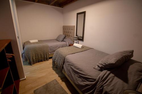 a bedroom with two beds and a mirror at Hotel Tierra de Parras in Chillán