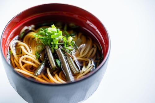 a red bowl filled with noodles and green onions at ANA Crowne Plaza Matsuyama by IHG in Matsuyama