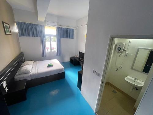 a room with a bed and a bathroom with a shower at Kuala Melaka Inn in Pantai Cenang