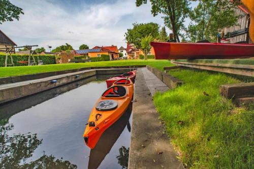 a row of kayaks sitting on the side of a canal at Appartements Am Spreewaldfliess, Schlepzig in Schlepzig