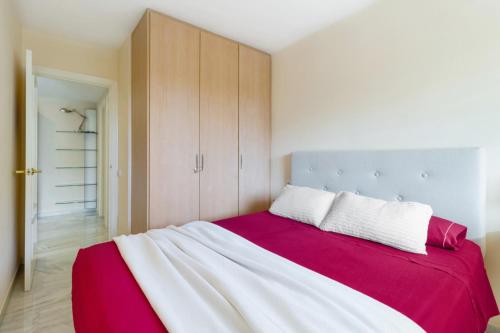 a bedroom with a large bed with a red and white blanket at Benalmadena with seasonal pool & parking near the beach in Arroyo de la Miel