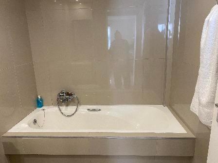a white bath tub in a bathroom with a shower at Nautica 2 Bedroom Beachfront Apartment with Sea Views in Bloubergstrand