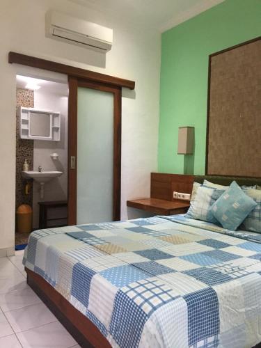 ein Schlafzimmer mit einem Bett mit einer blau-weißen Decke in der Unterkunft Nadialit in Seminyak