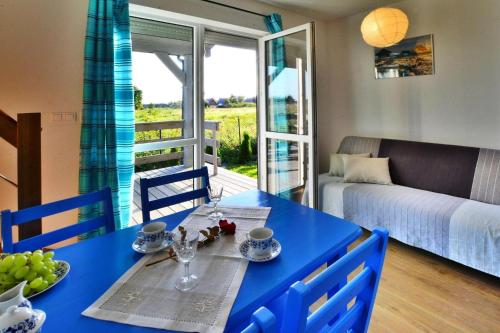 a blue table and chairs in a living room with a bed at Holiday bungalow for 4 people Jaroslawiec in Jarosławiec