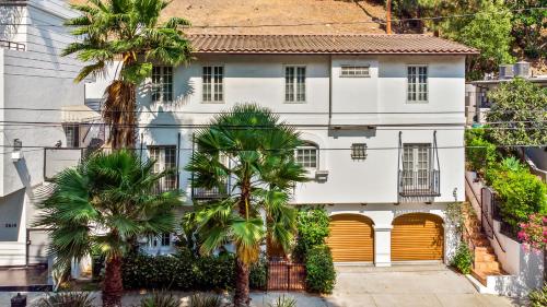 a white house with yellow doors and palm trees at Hollywood Hills Homestay in Los Angeles