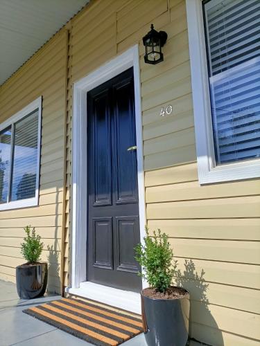 a black door on a house with two potted plants at Peel Cottage in Bendigo
