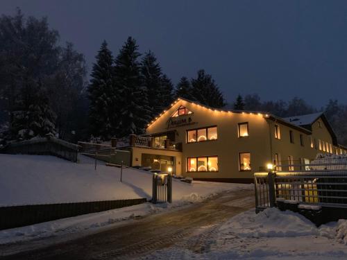 a house with lights on it in the snow at Pension Pöhlbergblick Annaberg in Annaberg-Buchholz