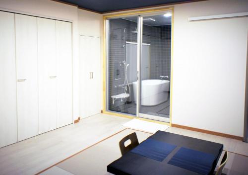 a room with a table and a tub in a bathroom at ATAMI SPRING TERRACE HOTEL in Atami