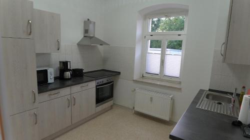 a kitchen with white cabinets and a sink and a window at Otto der Reiche in Ballenstedt