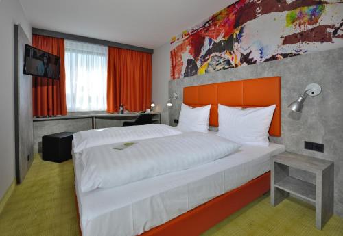 a bedroom with a large bed with an orange headboard at SleepySleepy Hotel Gießen in Gießen