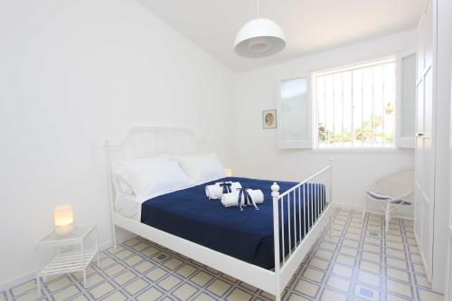 una camera bianca con un letto con una coperta blu di Sud Est Le Case di Elisa a Marina di Ragusa