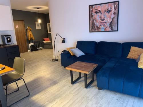a living room with a blue couch and a table at Apartament na Leśnej in Pobierowo