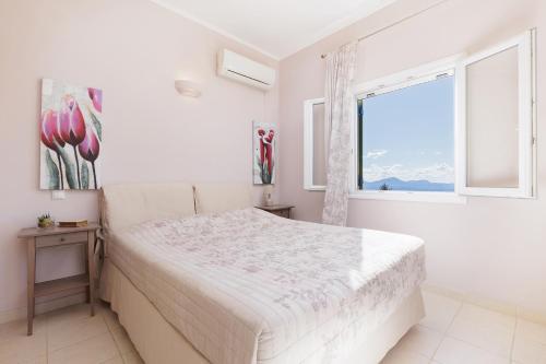 a white bedroom with a bed and a window at Villa Elia, Spartylas Corfu in Spartýlas