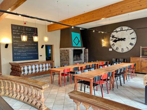 a restaurant with a large clock and tables and chairs at La Recreation in Somme-Leuze