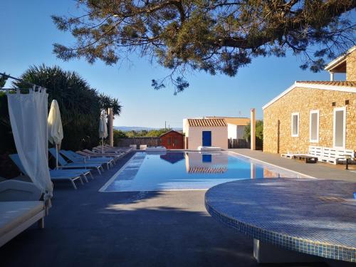 a swimming pool with tables and umbrellas next to a building at Casa rural isleña in Sant Francesc Xavier