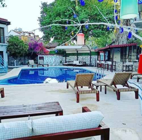 um grupo de bancos sentados ao lado de uma piscina em Nehir Dalyan Boutique Otel em Ortaca