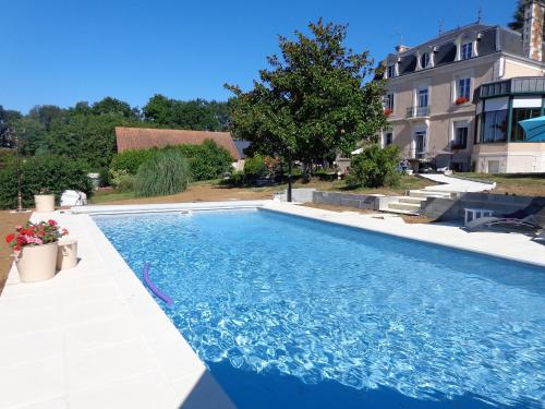 une piscine avec de l'eau bleue devant un immeuble dans l'établissement La Maison Ribotteau - The Coach House Gîte, à LʼIsle-Jourdain