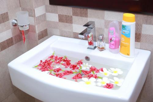 een witte wastafel met bloemen in de badkamer bij Charly Villa in Haburugala
