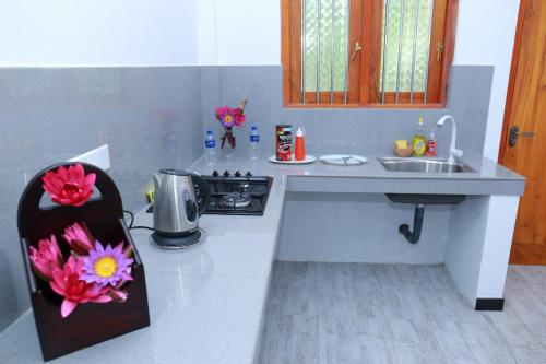 a kitchen with a sink and a counter with flowers on it at Charly Villa in Haburugala